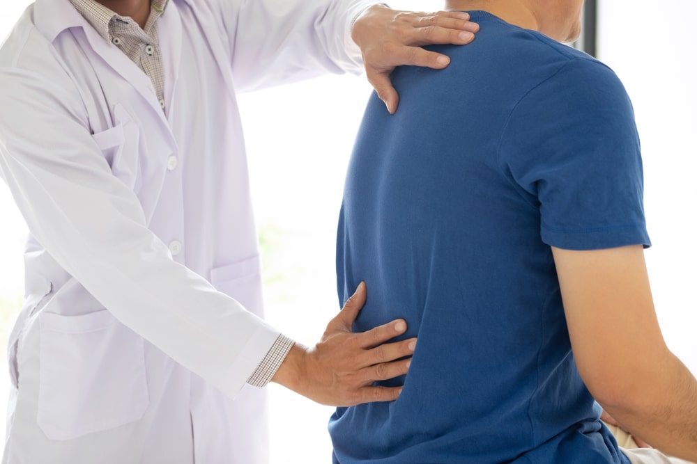 doctor has two hands on patient back to check alignment